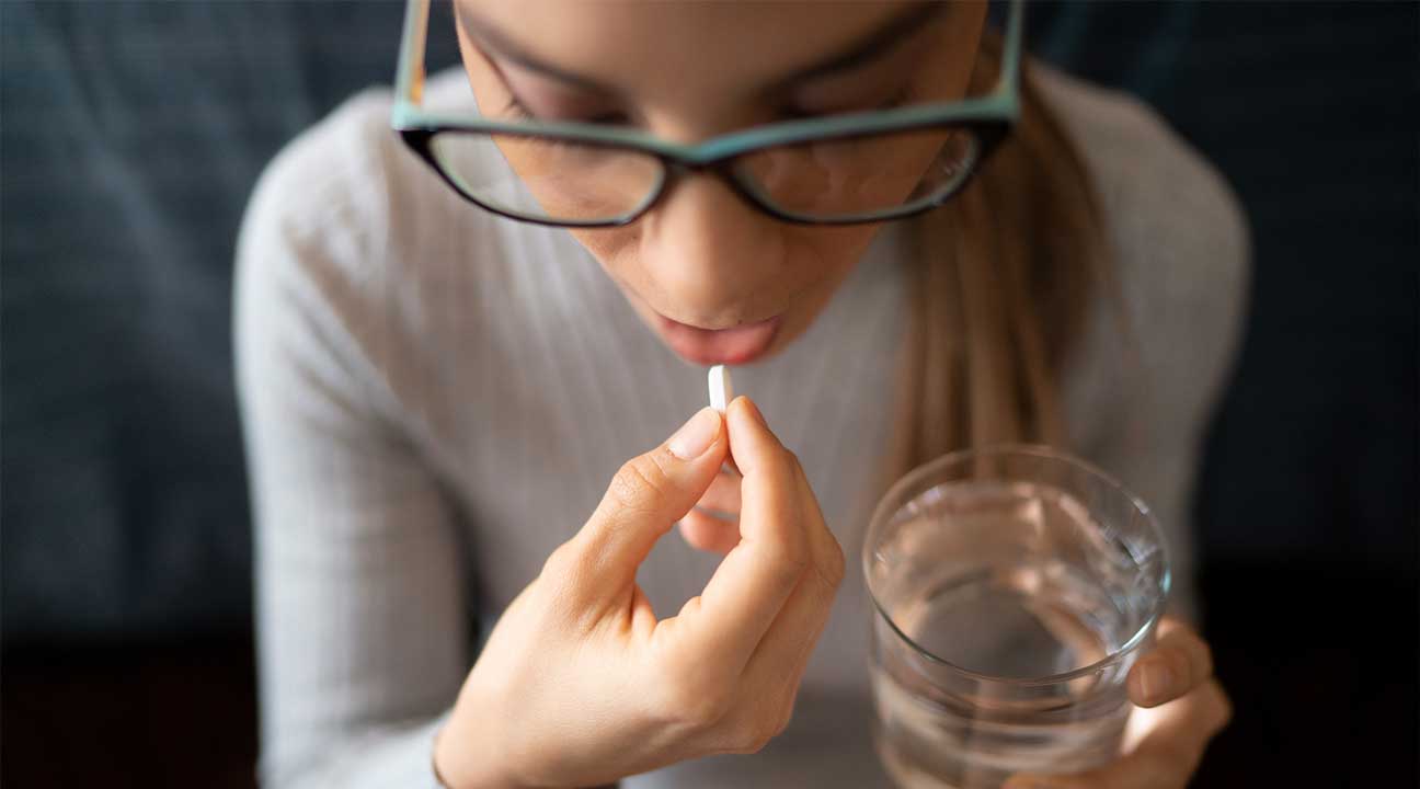 young women taking a prescription opioid white pill