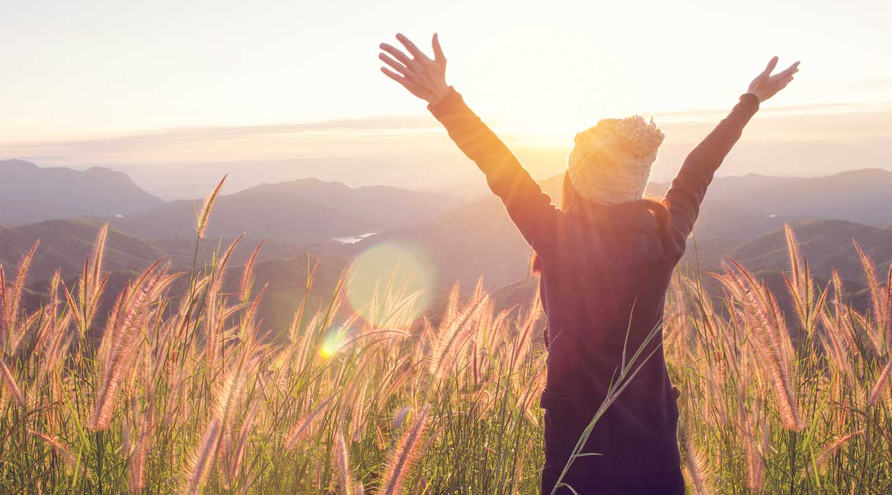woman holding up her arms during sunrise celebrating her sobriety