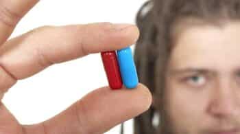 young man holding two pills - The Dangers Of Mixing Red Dawn Sleepwalker Pills & Ephedrine