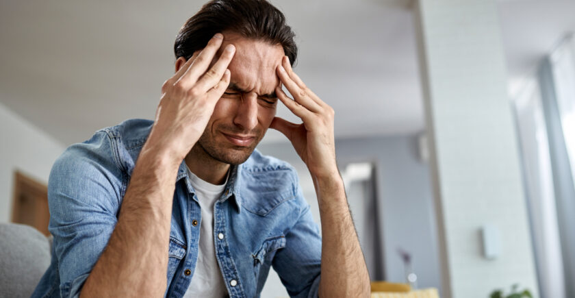 Distressed man with his hands pressed into his temple